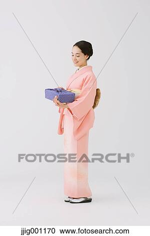Stock Image - Young Japanese woman in a traditional kimono against white background. Fotosearch