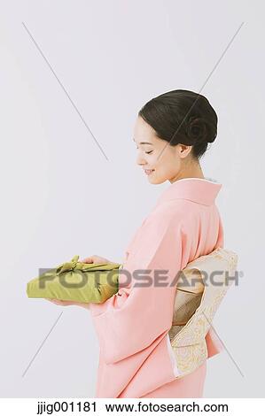 Stock Image - Young Japanese woman in a traditional kimono against white background. Fotosearch