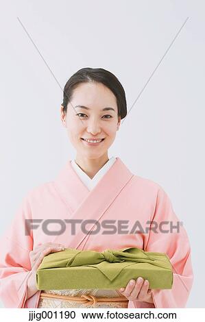 Stock Image - Young Japanese woman in a traditional kimono against white background. Fotosearch