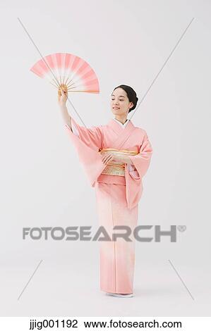 Stock Image - Young Japanese woman in a traditional kimono against white background. Fotosearch