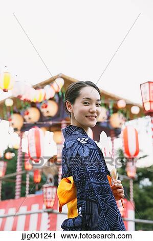 Stock Image - Young Japanese woman in a traditional kimono at a summer festival. Fotosearch