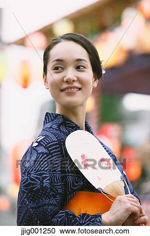 Stock Image - Young Japanese woman in a traditional kimono at a summer festival. Fotosearch