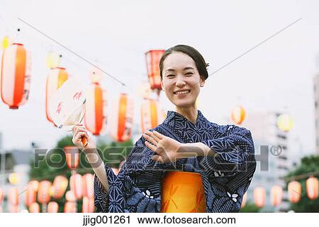 Stock Image - Young Japanese woman in a traditional kimono at a summer festival. Fotosearch