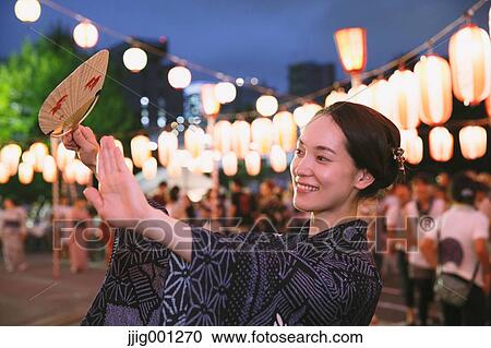 Stock Image - Young Japanese woman in a traditional kimono at a summer festival. Fotosearch
