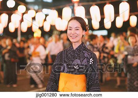 Stock Image - Young Japanese woman in a traditional kimono at a summer festival. Fotosearch
