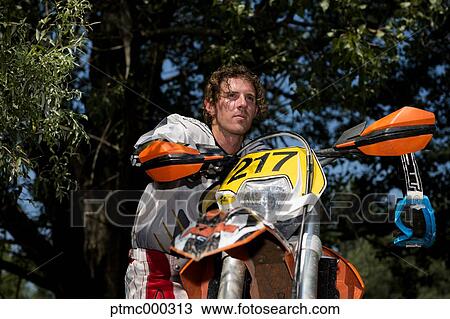 Stock Image - Young Man Relaxing Besides Motocross Bike in Countryside. Fotosearch