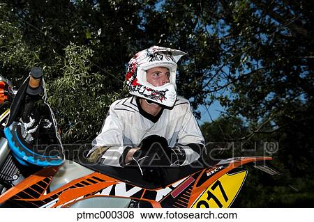 Stock Photo - Young Man Relaxing Besides Motocross Bike in Countryside. Fotosearch