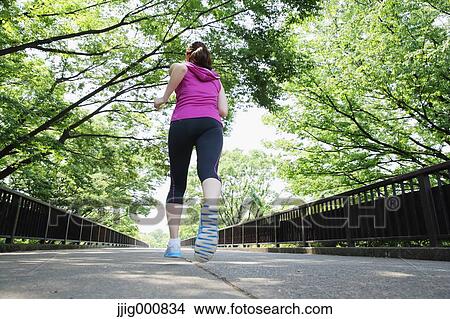Picture - Young Japanese girl running in the park. Fotosearch