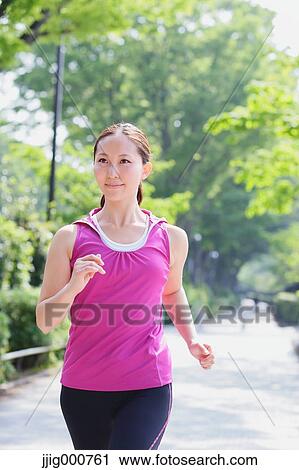 Stock Image - Young Japanese girl running in the park. Fotosearch