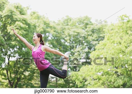 Stock Image - Young Japanese girl stretching in the park. Fotosearch