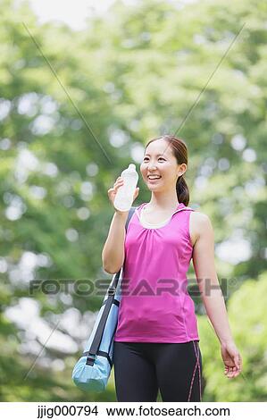 Young Japanese girl with water bottle after training in the park View Large Photo Image Picture - Young Japanese girl with water bottle after training in the park. Fotosearch