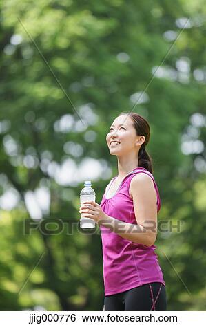 Young Japanese girl with water bottle after training in the park View Large Photo Image Stock Photograph - Young Japanese girl with water bottle after training in the park. Fotosearch