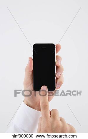 Stock Image - Mid adult man holding smartphone. Fotosearch