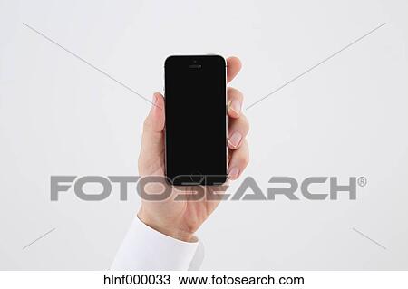 Stock Image - Mid adult man holding smartphone. Fotosearch
