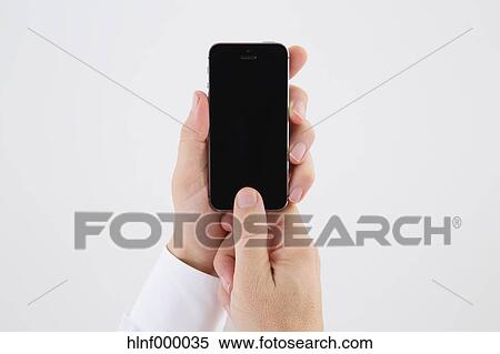 Stock Photography - Mid adult man holding smartphone. Fotosearch