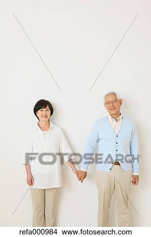 Picture - Senior adult Japanese couple against white wall. Fotosearch