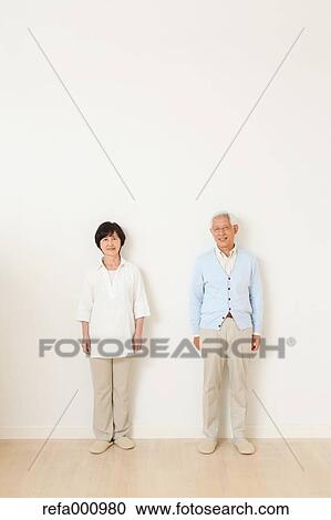 Stock Image - Senior adult Japanese couple against white wall. Fotosearch