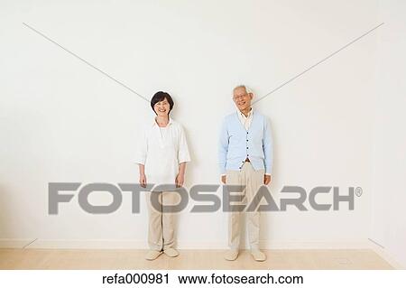 Stock Image - Senior adult Japanese couple against white wall. Fotosearch