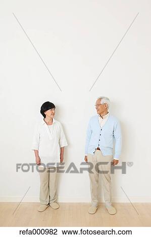 Stock Image - Senior adult Japanese couple against white wall. Fotosearch
