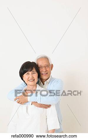 Stock Image - Senior adult Japanese couple against white wall. Fotosearch
