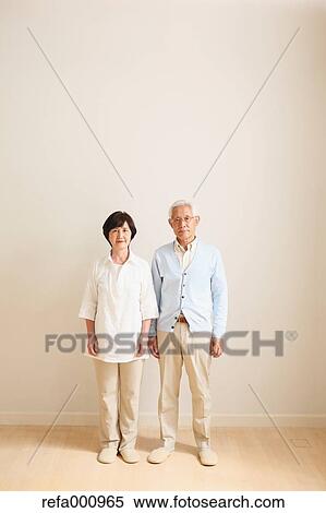 Stock Photography - Senior adult Japanese couple against white wall. Fotosearch
