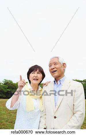 Stock Image - Senior adult Japanese couple in a park. Fotosearch
