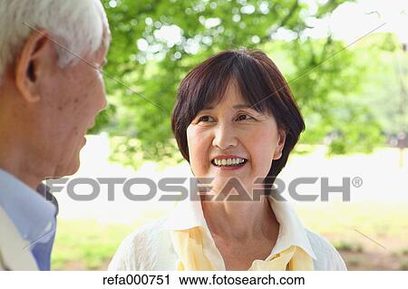 Stock Image - Senior adult Japanese couple in a park. Fotosearch