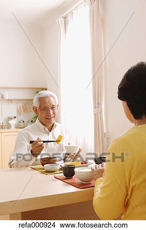 Picture - Senior adult Japanese couple in the kitchen. Fotosearch