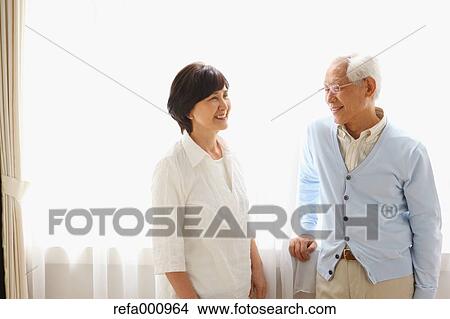 Picture - Senior adult Japanese couple in the living room. Fotosearch