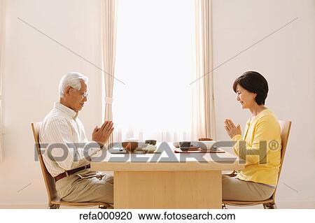 Stock Image - Senior adult Japanese couple in the kitchen. Fotosearch