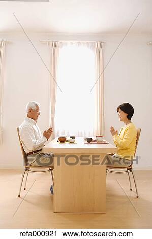 Stock Image - Senior adult Japanese couple in the kitchen. Fotosearch