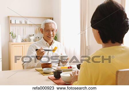 Stock Image - Senior adult Japanese couple in the kitchen. Fotosearch