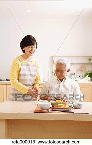Stock Photo - Senior adult Japanese couple in the kitchen. Fotosearch