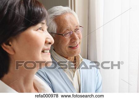 Stock Photo - Senior adult Japanese couple in the living room. Fotosearch