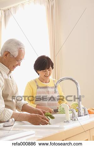 Stock Photograph - Senior adult Japanese couple in the kitchen. Fotosearch