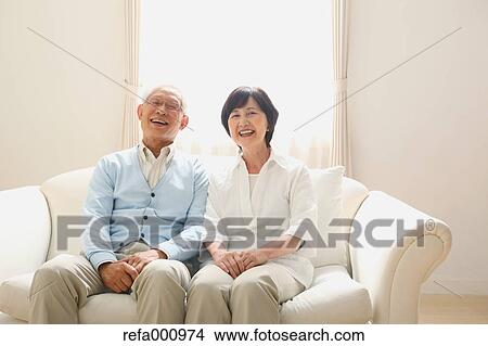 Picture - Senior adult Japanese couple on the sofa. Fotosearch