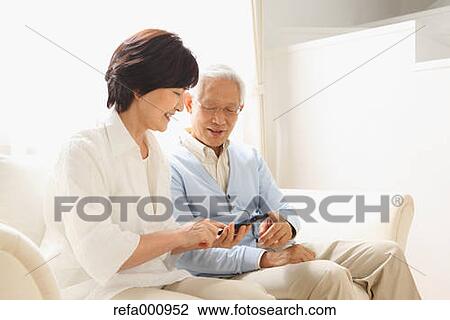 Stock Image - Senior adult Japanese couple on the sofa. Fotosearch