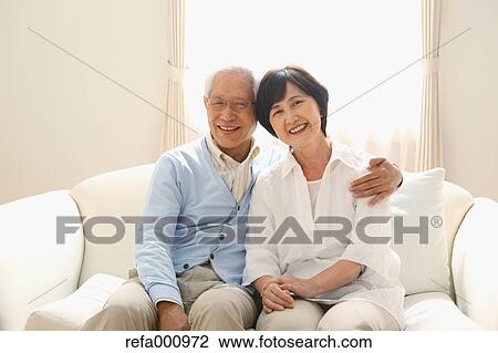 Stock Image - Senior adult Japanese couple on the sofa. Fotosearch