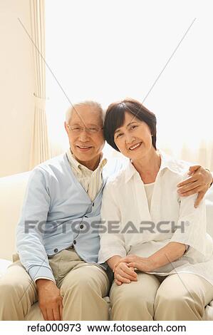 Stock Image - Senior adult Japanese couple on the sofa. Fotosearch