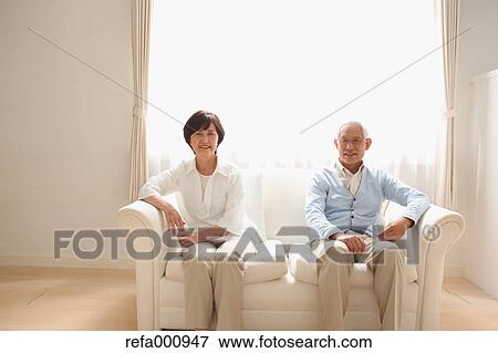 Stock Photo - Senior adult Japanese couple on the sofa. Fotosearch