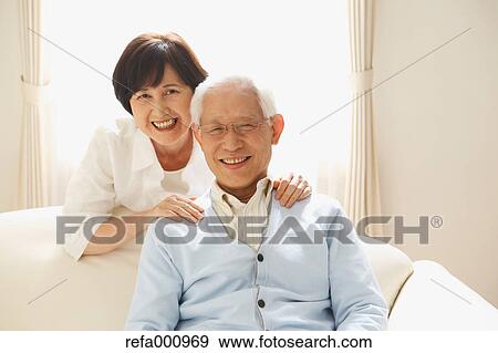 Stock Photo - Senior adult Japanese couple on the sofa. Fotosearch
