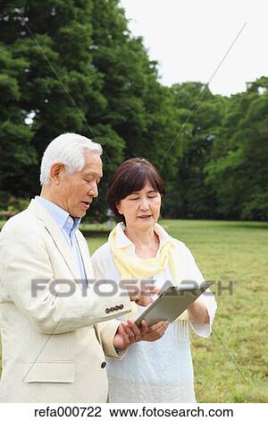 Senior adult Japanese couple with tablet in a park View Large Photo Image Stock Image - Senior adult Japanese couple with tablet in a park. Fotosearch
