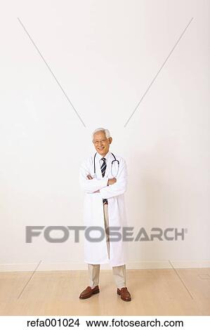 Picture - Senior adult Japanese doctor against white wall. Fotosearch