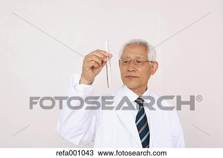 Stock Image - Senior adult Japanese doctor against white wall. Fotosearch