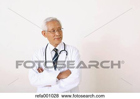 Stock Photo - Senior adult Japanese doctor against white wall. Fotosearch