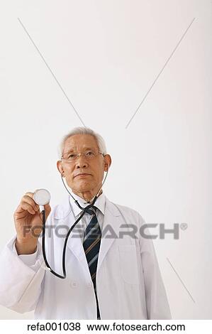 Stock Photo - Senior adult Japanese doctor against white wall. Fotosearch