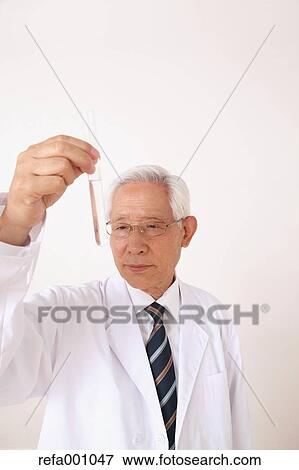 Stock Photo - Senior adult Japanese doctor against white wall. Fotosearch