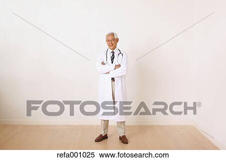 Stock Photography - Senior adult Japanese doctor against white wall. Fotosearch
