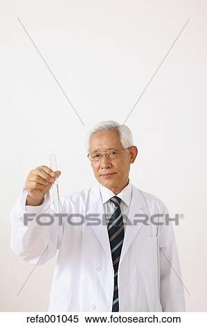 Stock Photography - Senior adult Japanese doctor against white wall. Fotosearch