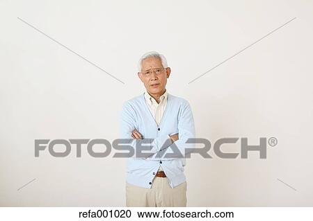 Stock Image - Senior adult Japanese man against white wall. Fotosearch